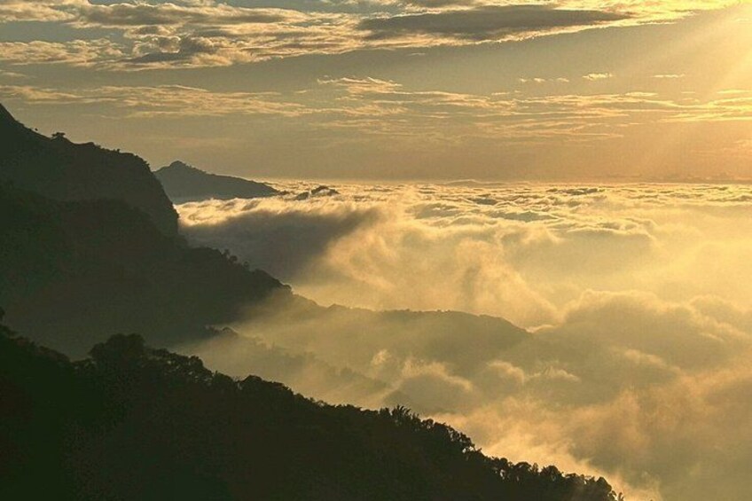 Un paisaje montañoso con nubes bajas y luz del sol filtrándose entre las cumbres. 2
