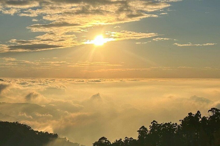 A sunrise over a mountainous landscape with clouds below the peak. 2
