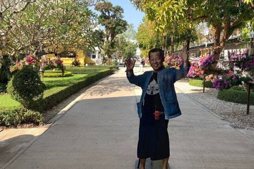 Una persona parada en un camino pavimentado, con árboles y flores a ambos lados. 4