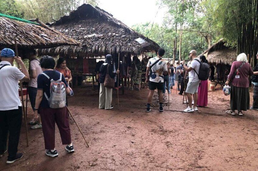 Un grupo de personas de pie en un entorno rural con construcciones de techo de paja. 2