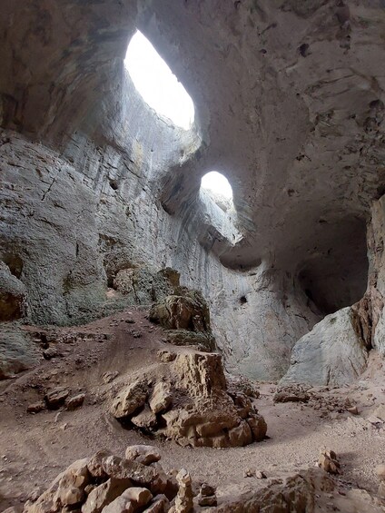 A cave interior with natural rock formations and a small opening allowing light to enter. 4