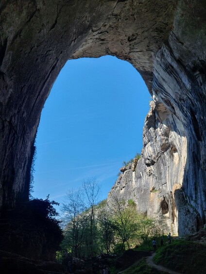 A natural rock arch formation with a clear blue sky visible through the opening. 2