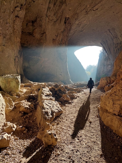 A person walking through a rocky cave passage. 3