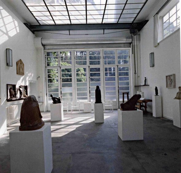 An art gallery with sculptures on pedestals, large windows, and a high ceiling. 4