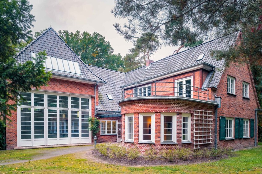 A red brick house with a garage, a curved section, and green shutters. 1