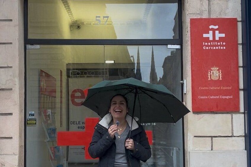 Una persona in piedi di fronte a un edificio con un cartello rosso che riporta 'Instituto Cervantes'. 4