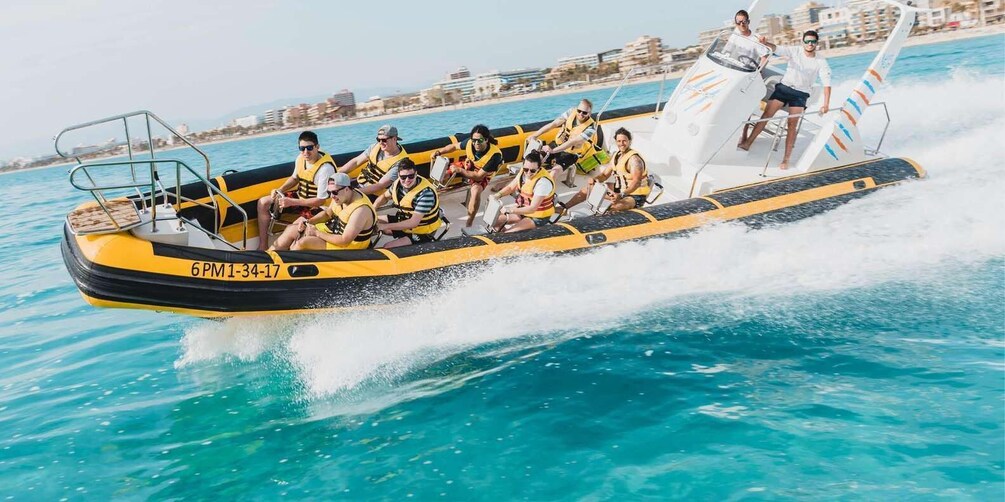 A yellow and black speedboat with passengers in life vests, moving through turquoise water with a cityscape in the background. 1