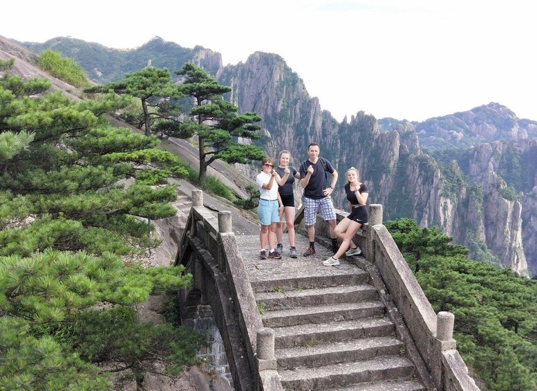 A group of people on a stone staircase surrounded by pine trees and steep cliffs. 1