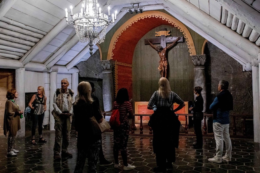 A group of people inside a church with a crucifix and a chandelier. 4