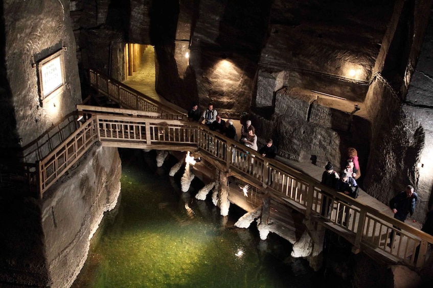 A cave with a wooden staircase and a pool of water. 2