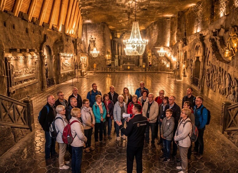 A group of people in a historic building with stone walls, a chandelier, and a stone floor. 3