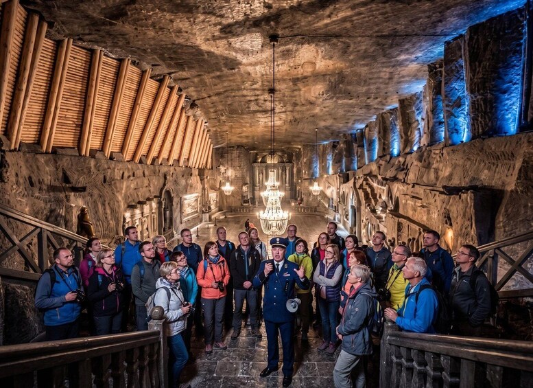 A group of people inside a cave with wooden structures on the sides and a chandelier in the center. 4