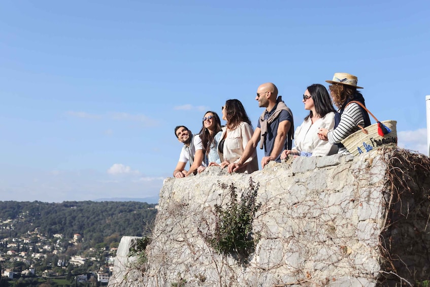 A group of people standing on a stone wall overlooking a town. 4