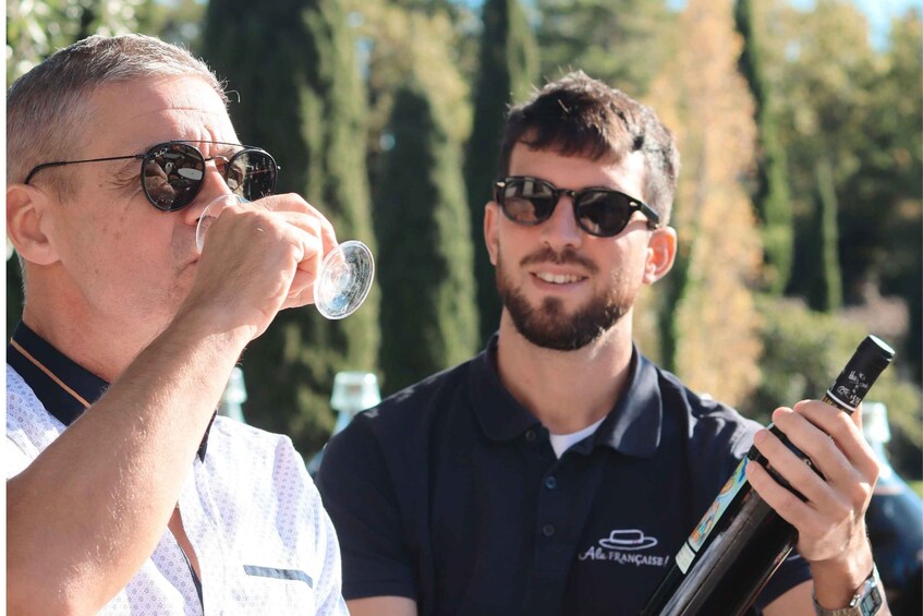 Two people outdoors, one holding a bottle. 1