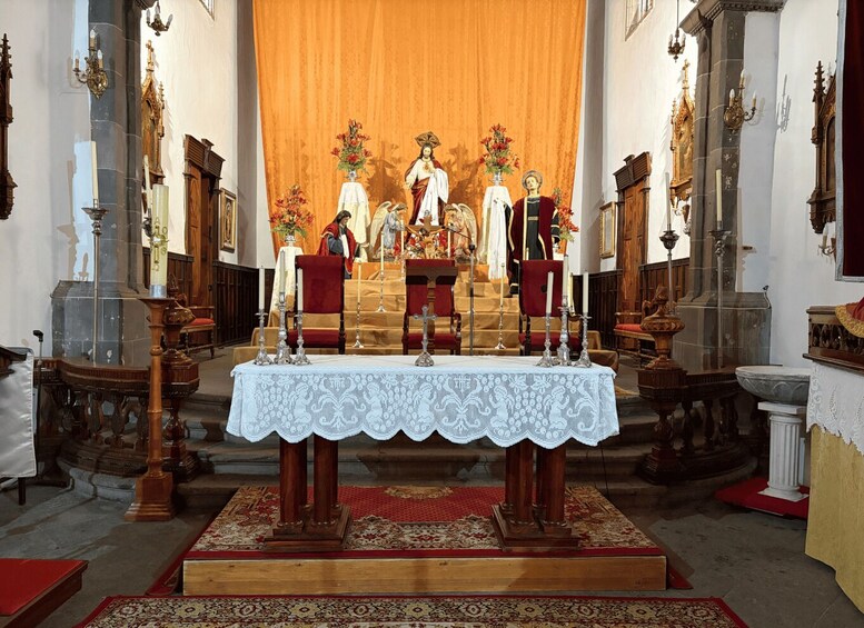 An ornate church interior with a central altar, religious statues, and a red carpeted floor. 3