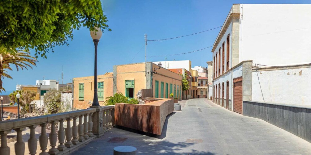 A sunlit street with buildings, a lamppost, and a clear blue sky. 4