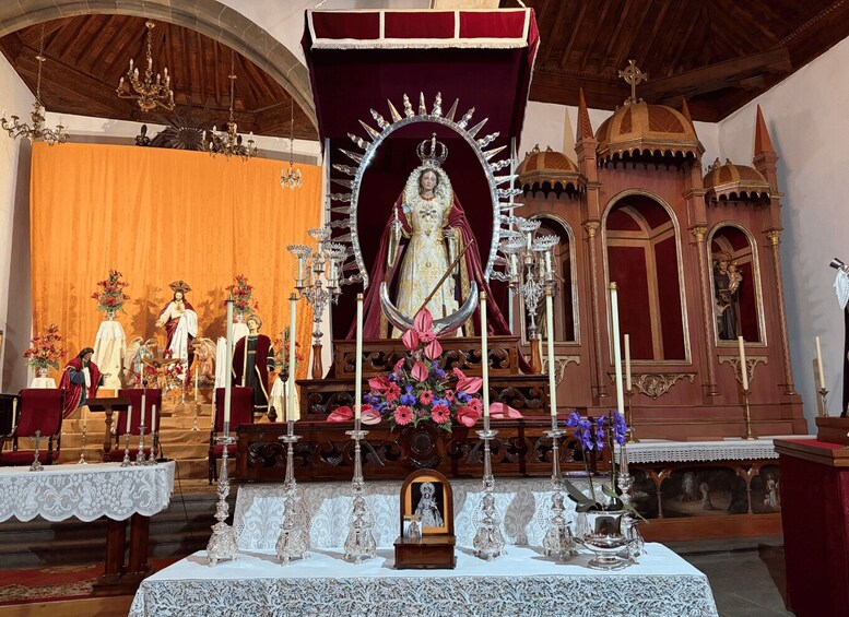 A religious altar with a statue of a saint, candles, and flowers. 4