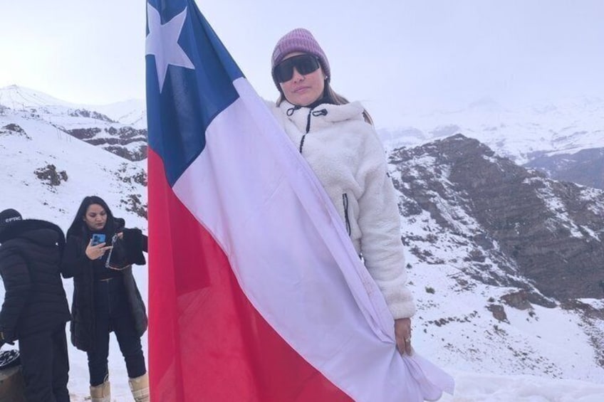 Una persona sosteniendo una bandera con una estrella y una cordillera al fondo. 4
