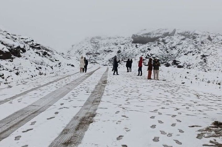 Un sendero nevado en la montaña, con huellas y un grupo de personas caminando. 5