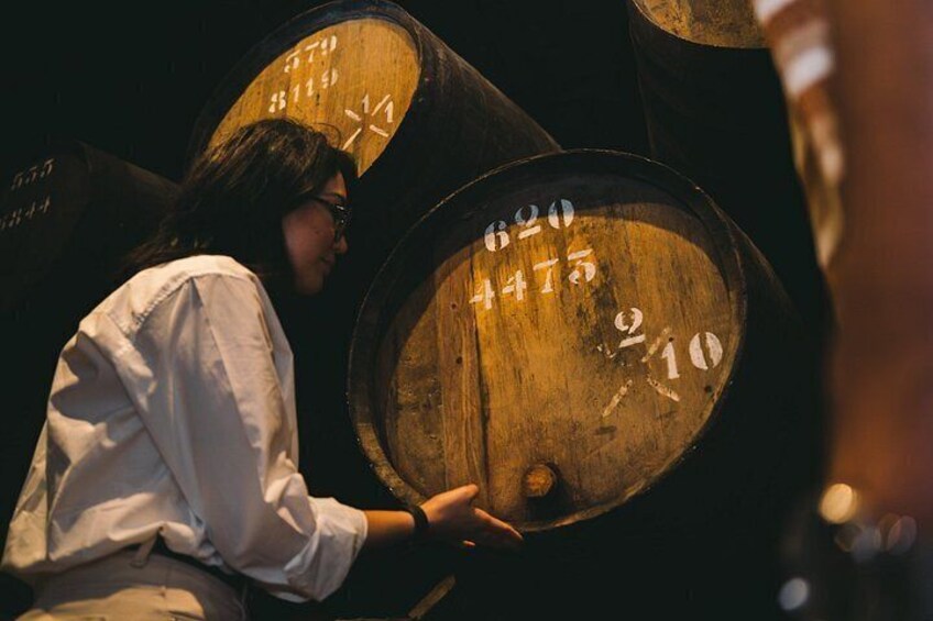A person inspecting large wooden barrels with numbers on them. 3