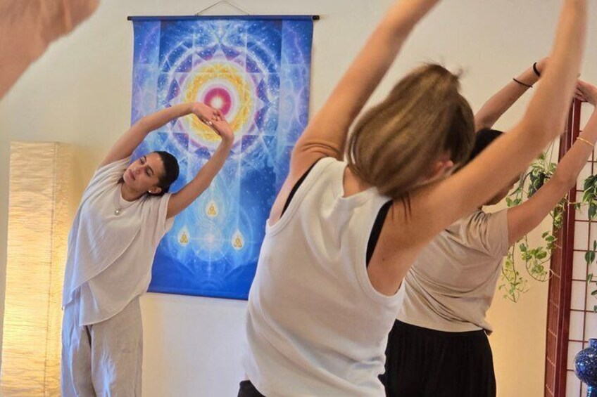 Two people stretching in a room with a blue tapestry and a plant. 2