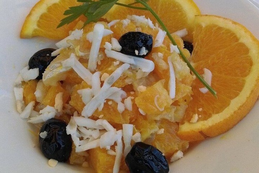Ein Teller mit geriebenem Käse, Orangenscheiben und schwarzen Oliven. 4