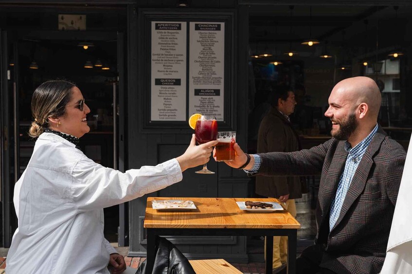 Two people toasting with drinks at a table with menus in the background. 5