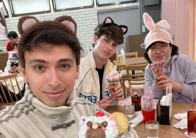 Three people at a table with food and drinks, one wearing a bear hat and another with a bunny hat. 5