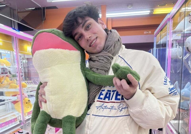 A person holding a large plush toy in a store with shelves of toys in the background. 2