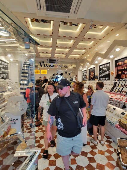 A chocolate shop interior with a checkered floor, a glass display case, and a ceiling with recessed lighting. 4