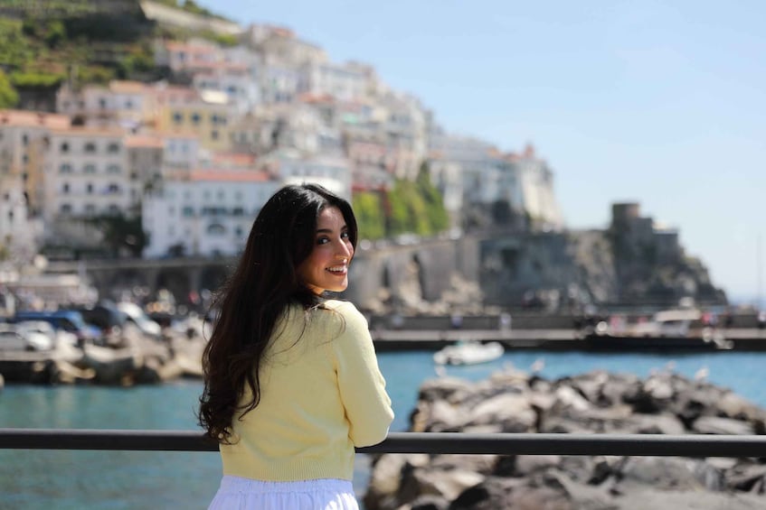 A person standing by a waterfront with buildings in the background. 3