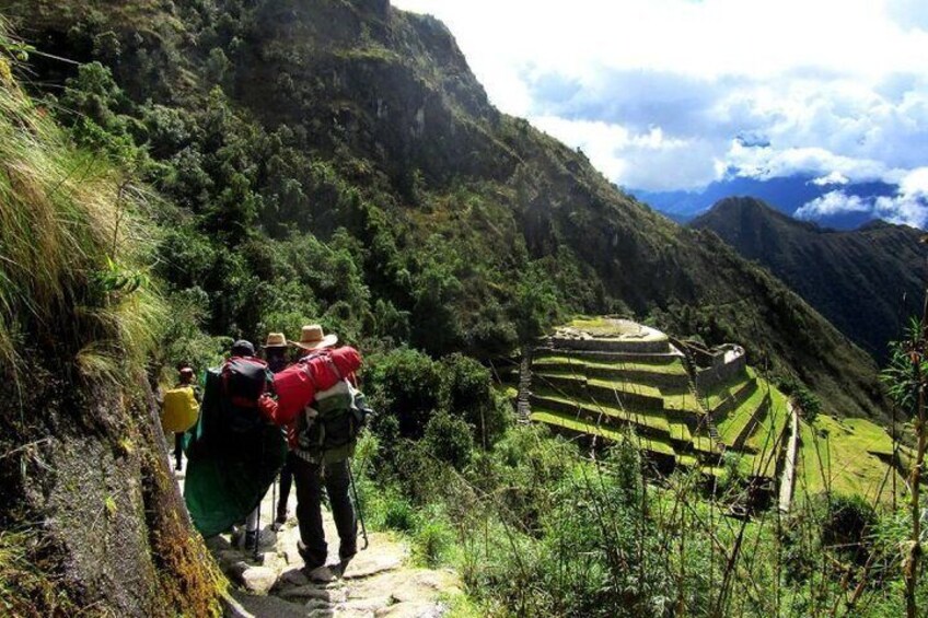 A group of hikers on a mountain trail with terraced fields in the background. 3