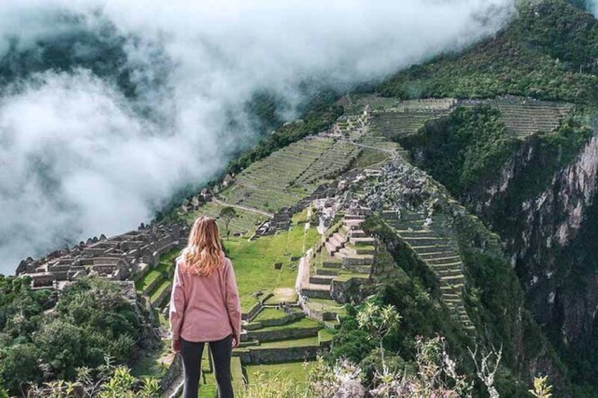 A person standing on a hill overlooking terraced fields and ancient ruins. 2