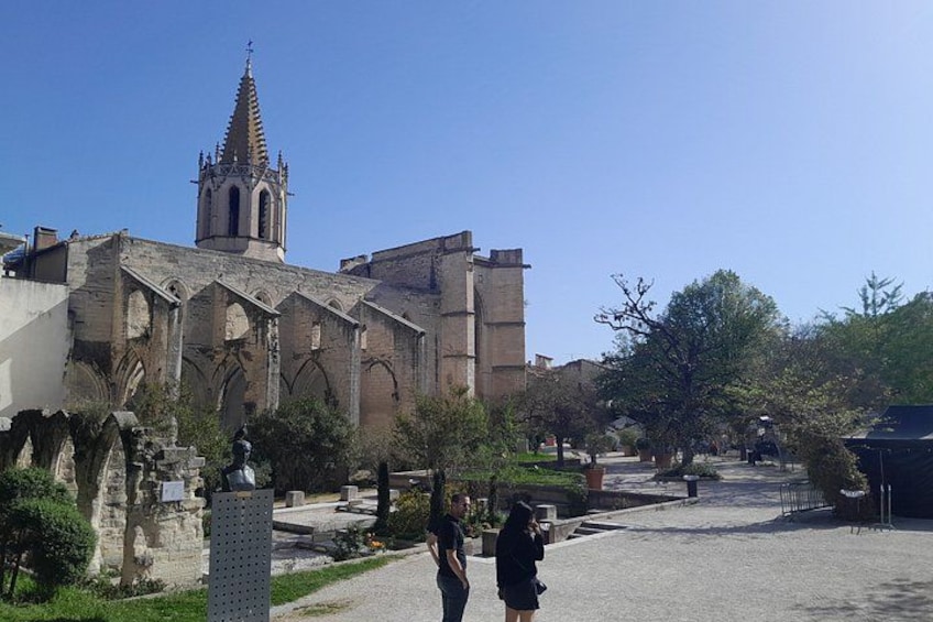 A historic church with a tall spire, a paved courtyard, and a statue. 2
