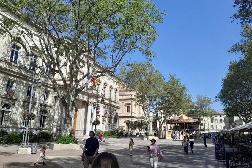 A historic square with classical architecture, a fountain, and people walking. 4