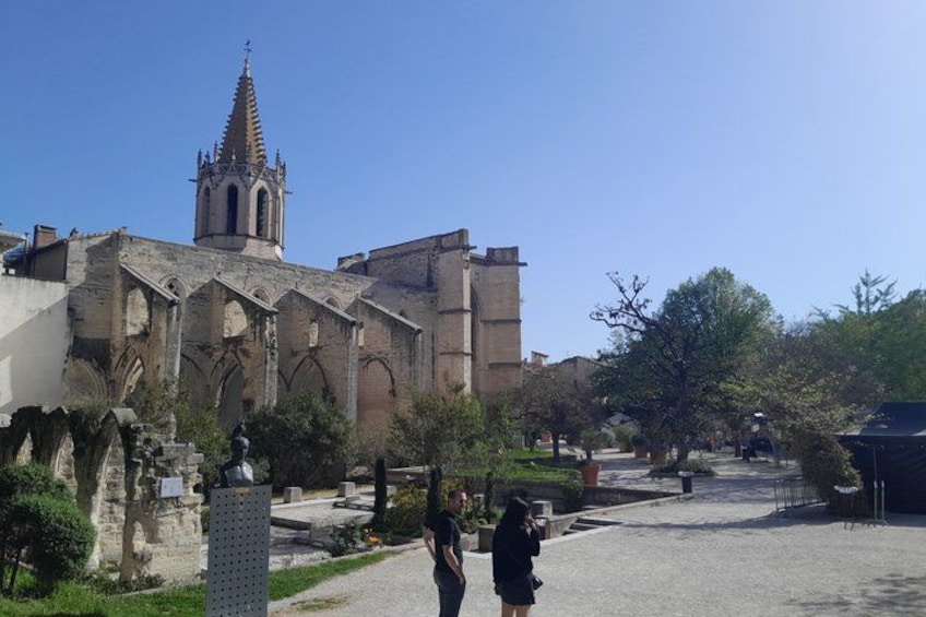 A historic church with a tall spire, a paved courtyard, and a statue. 4