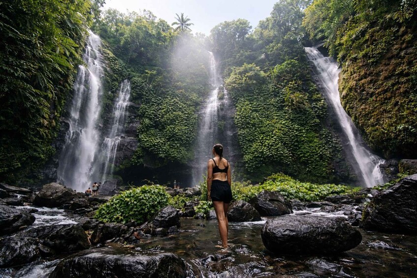 A waterfall with a person standing in the water. 5