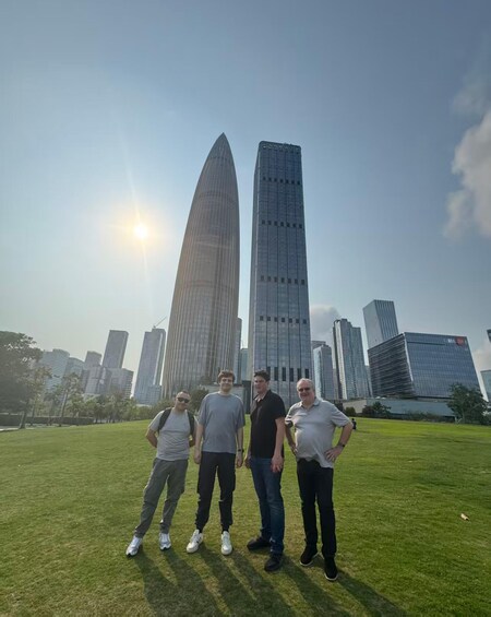 Four people standing on grass with a city skyline in the background. 3