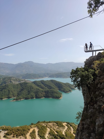 A high vantage point overlooking a turquoise lake surrounded by forested hills. 2