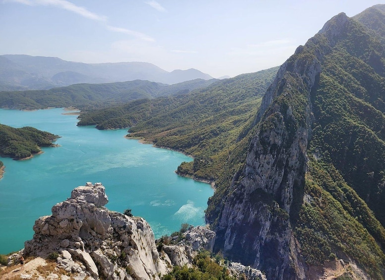 A mountainous landscape with a turquoise lake surrounded by dense forests and rocky cliffs. 4