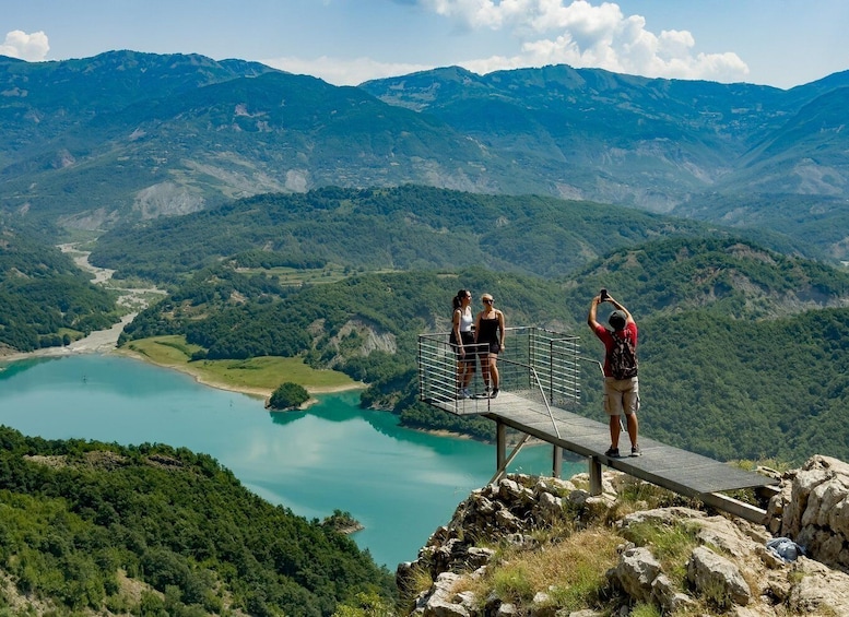 A wooden viewing platform overlooking a turquoise lake with mountains in the background. 1