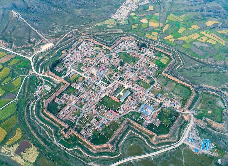 An aerial view of a fortified town with a central square, surrounded by walls and fields. 5