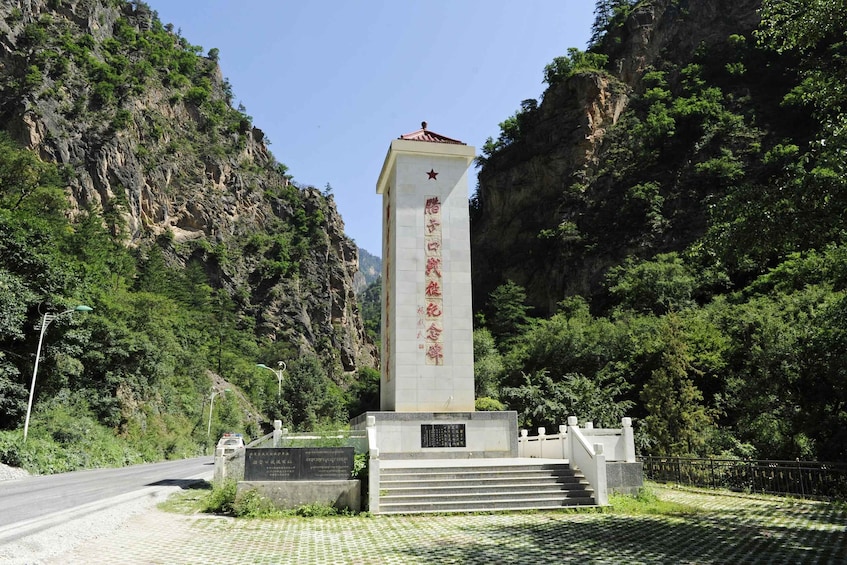 A monument with inscriptions, surrounded by a mountainous landscape. 3
