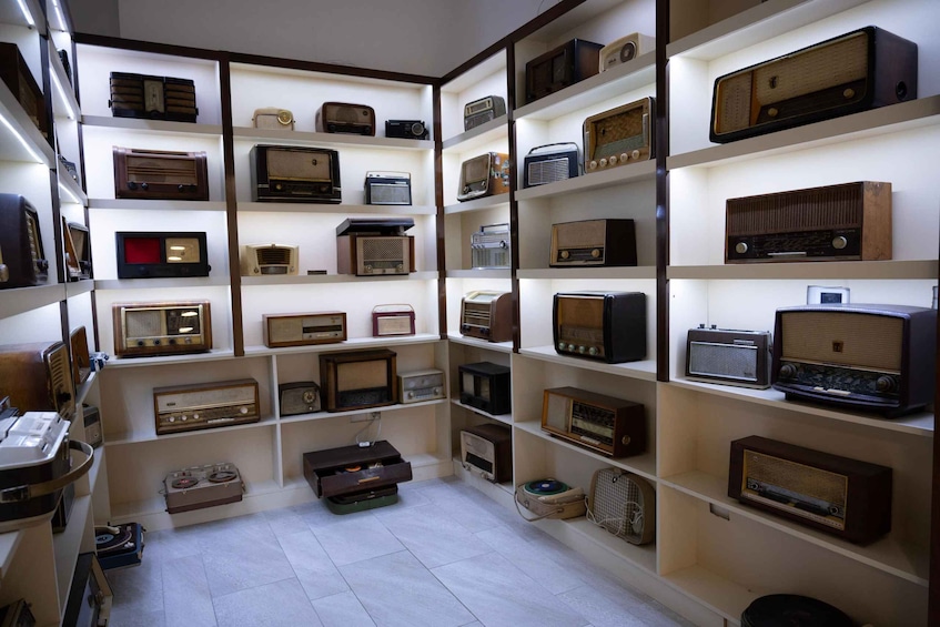 A room filled with various vintage radios and audio equipment on shelves. 4
