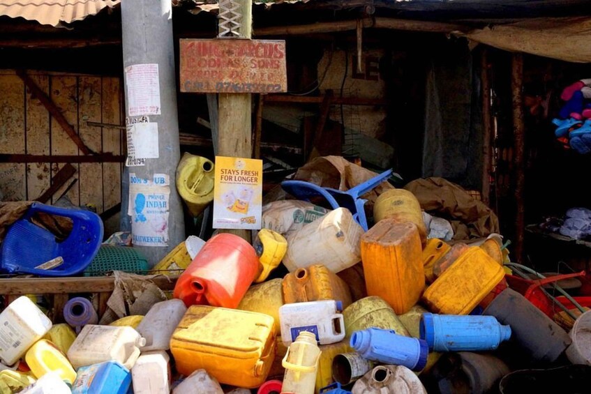 Une pile de récipients en plastique usagés et un panneau avec du texte. 2