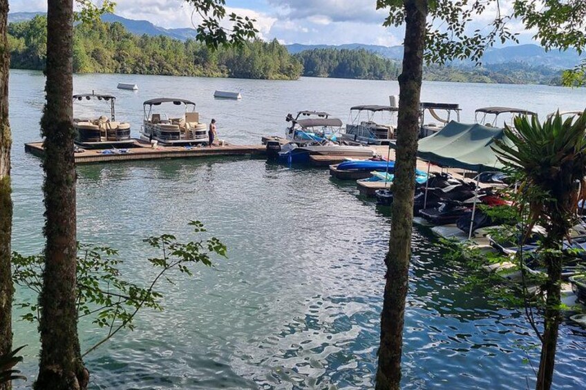 A lake with boats docked, surrounded by trees and mountains in the background. 3