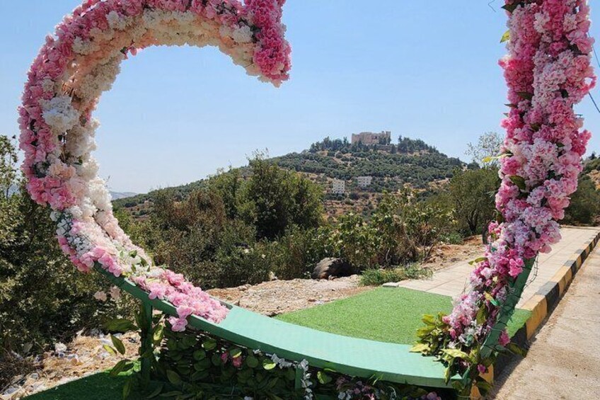 A heart-shaped floral arch with a view of a hilltop castle. 4