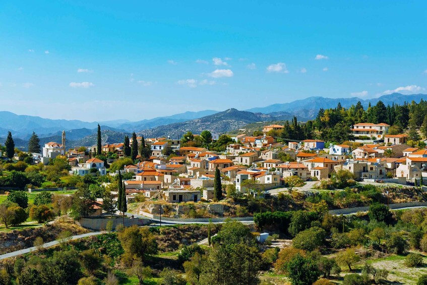 A coastal village with terracotta-roofed houses, a prominent church, and a mountainous backdrop. 2
