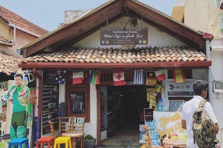 A traditional tea shop with a signboard, outdoor seating, and a small entrance. 2