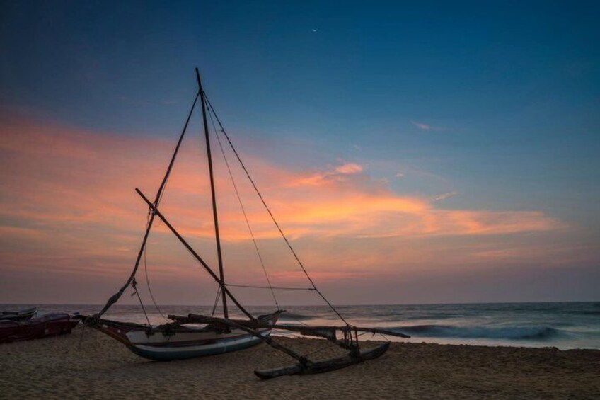 A beach with two traditional boats and a clear sky. 5